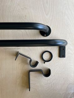 two black metal handles on a wooden surface next to a pair of wrench hooks