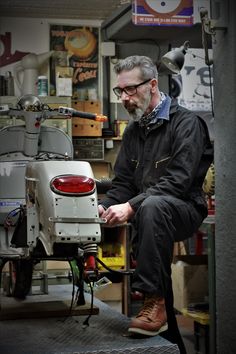 a man sitting on top of a motor scooter in a room filled with shelves