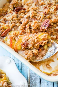 a casserole dish filled with fruit and pecans on top of a wooden table