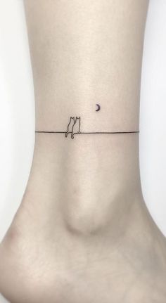 a small tattoo on the ankle of a woman's lower body, with a cat and moon in the distance