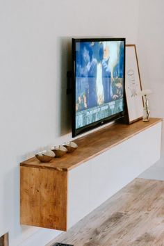 a flat screen tv sitting on top of a wooden shelf