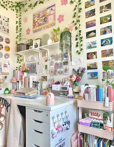 a room with lots of books and pictures on the wall, plants growing over the desk