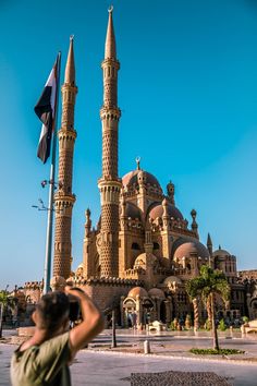 a man taking a photo of an old building with two spires in front of it