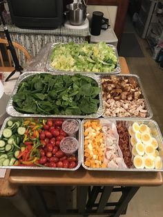 several trays filled with different types of vegetables on a table in front of a tv