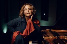 a woman sitting at a piano with her hands on her chin and looking off to the side