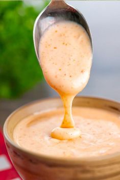 a spoon full of sauce being poured into a bowl