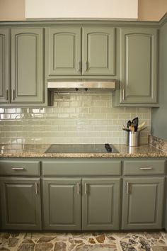 a kitchen with green cabinets and marble counter tops