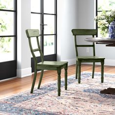 two green chairs sitting on top of a rug in front of a dining room table