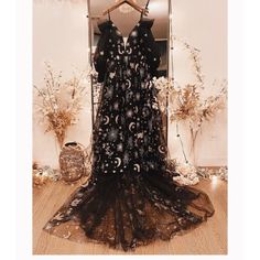 a black dress is on display in front of a mirror with flowers and branches around it