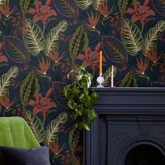 a green chair sitting next to a fireplace in front of a wallpapered wall