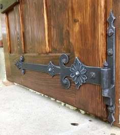 a close up of a door handle on a wooden door with metal hardware and flowers