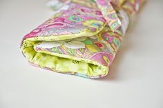 two pieces of fabric folded together on top of a white table with a green and pink flowered design