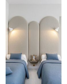 two beds in a room with white walls and blue bedding