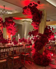 a room filled with lots of tables and chairs covered in red flowered centerpieces