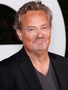 a man wearing glasses and a black suit