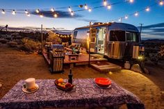 an rv is parked in the desert with lights strung over it's deck area