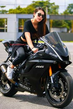 a woman sitting on top of a black motorcycle