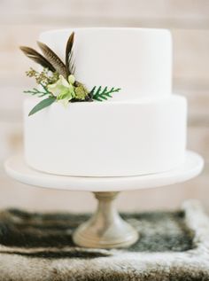 a white wedding cake with feathers and flowers on top