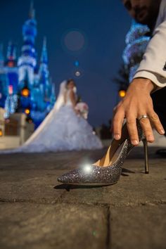 a person reaching for a shoe on the ground in front of a castle at night