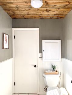 a white toilet sitting in a bathroom next to a wooden ceiling