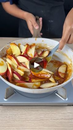 a person cutting apples into slices in a skillet