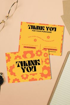 two thank you cards sitting on top of a desk next to a pair of glasses