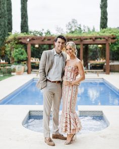 a man and woman standing in front of a pool