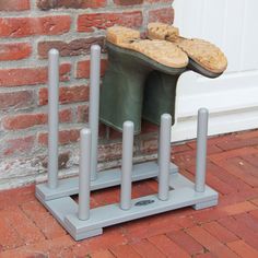 a pair of shoes that are sitting on top of a metal stand in front of a brick wall