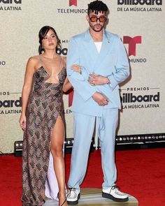 a man in a blue suit standing next to a woman on top of a skateboard