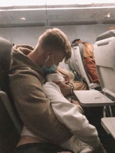 a man is sitting on an airplane and talking on his cell phone while holding a baby