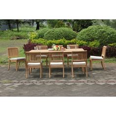 a wooden table and chairs sitting on top of a brick floor next to green bushes