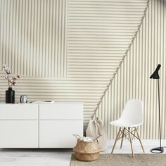 a white chair sitting next to a dresser in a room with stripes on the wall