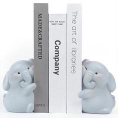 an elephant figurine sitting next to two bookends with books behind it