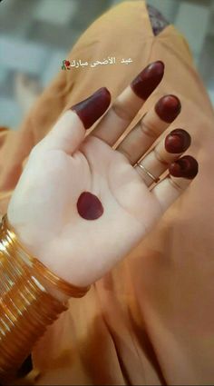 a woman's hand with red nail polish and gold bracelets on her wrist