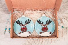 two decorated christmas ornaments in a box