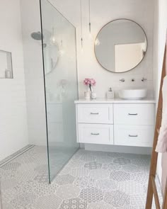 a bathroom with a large mirror, sink and walk - in shower next to a white tiled floor