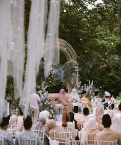 an outdoor wedding ceremony with white chairs and sheer draping hanging from the ceiling