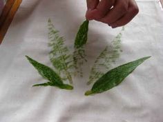 a person is painting some plants on a piece of white paper with watercolors