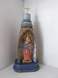 a statue of the virgin mary and child jesus on a blue base with gold trim