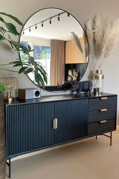 a large round mirror sitting on top of a dresser next to a potted plant