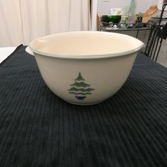 a white bowl sitting on top of a black table cloth next to a metal object