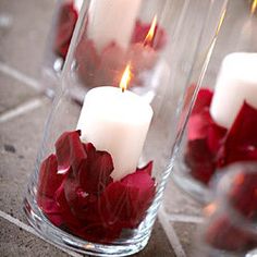 candles with red flowers in glass vases on tile floored area next to wall