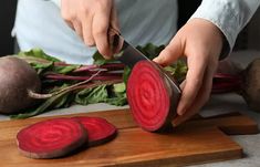 a person is cutting up some vegetables on a wooden board with two radishes