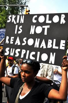 a woman holding a sign that says skin color is not reasonablee supplication