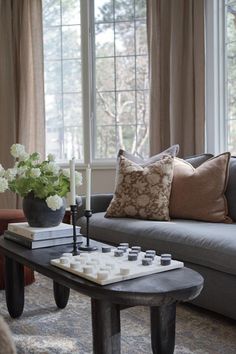 a living room with a couch, coffee table and vase filled with flowers on it