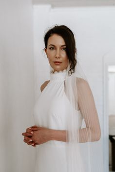 a woman in a white dress and veil posing for the camera with her hands on her hips