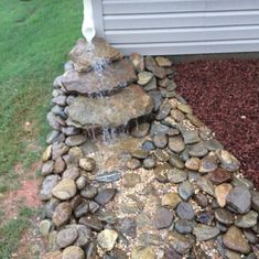 a rock waterfall in the middle of a yard