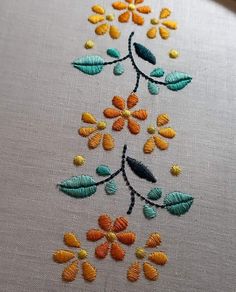 a close up of a piece of cloth with flowers and leaves embroidered on the fabric