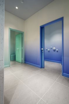 an empty room with blue doors and white tiles on the floor, in front of a green door