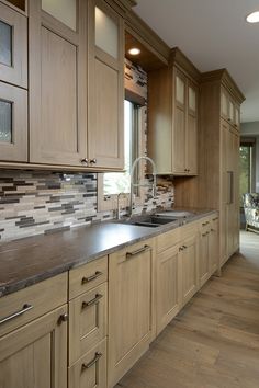 a large kitchen with wooden cabinets and stainless steel counter tops, along with hardwood flooring